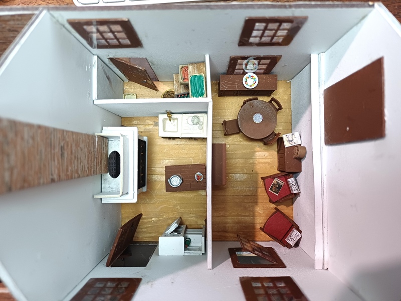 comme l'a remarqué Jean-Louis, il manquait une table, d'ailleurs une marmite y a été laissée ! une assiette de gateau attend le diner.<br />sur le potager, la vaisselle est à égoutter.<br />dans la salle, la TSF - seul luxe de ma maison - permet de suivre les nouvelles et les feuilletons. madame a crocheté deux naperons pour ne ps salir les dossiers des fauteuils, et même sur la table - oui, je sais il manque un vase ! ça viendra !<br />sur un fauteuil, le  dernier numéro du Petit Journal, et le dernier numéro du Catalogue Manufrance sur le buffet !